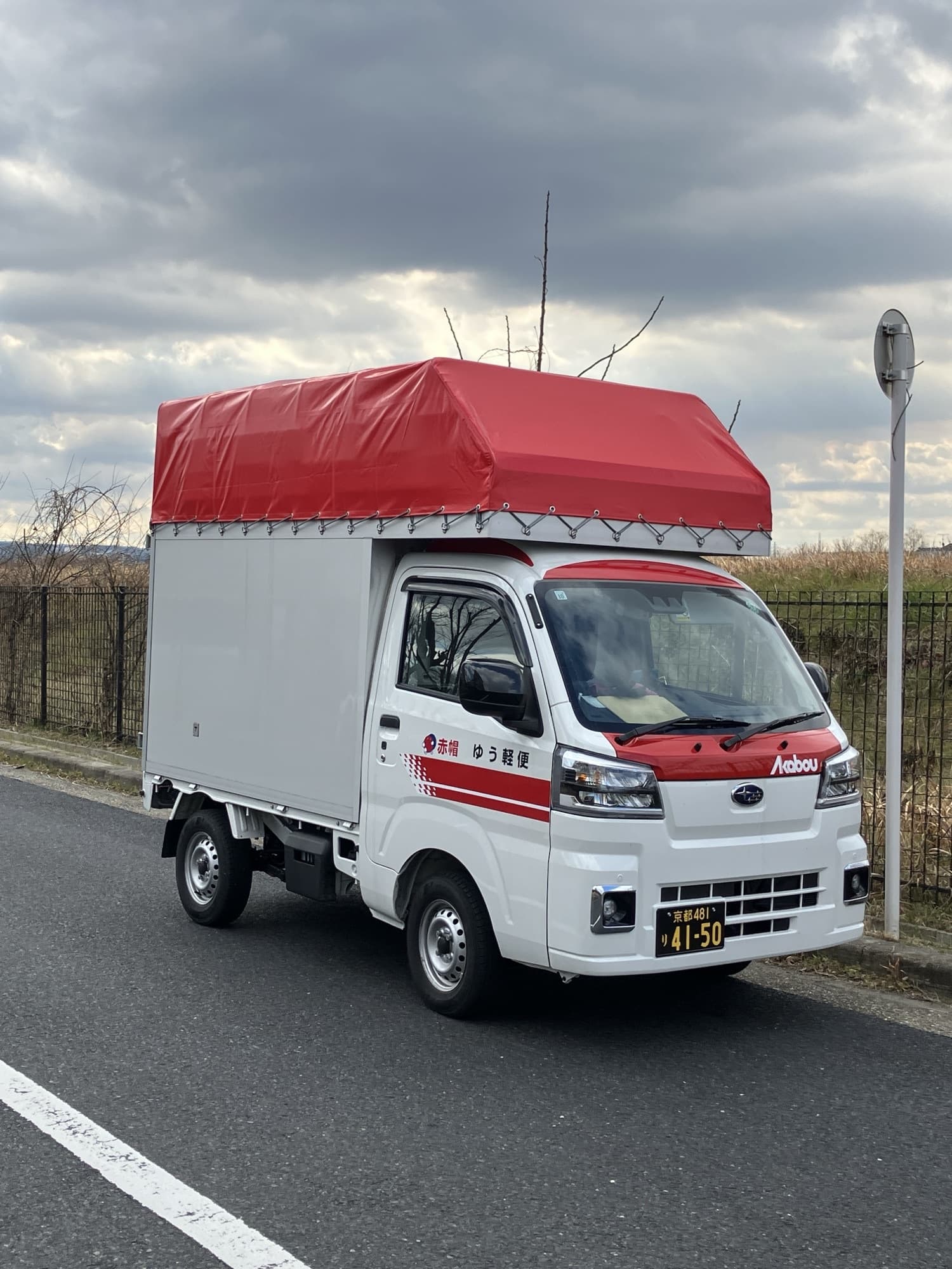 道路脇に停車する赤い軽貨物車